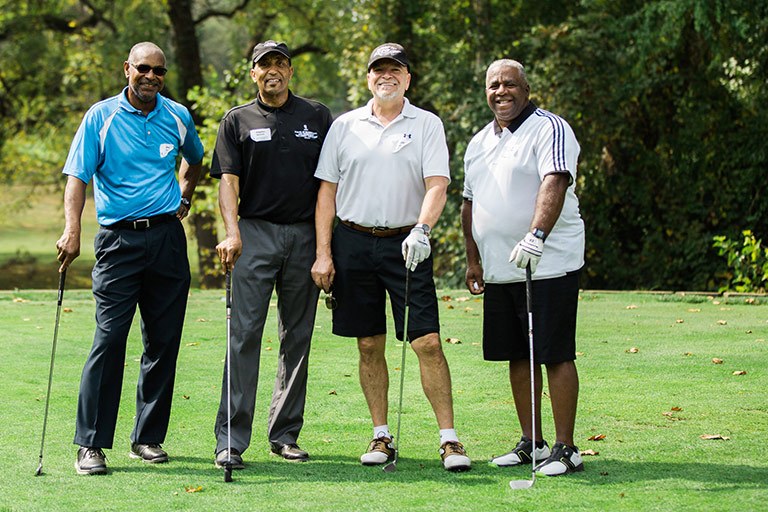 Four people stand together at a golf outing.